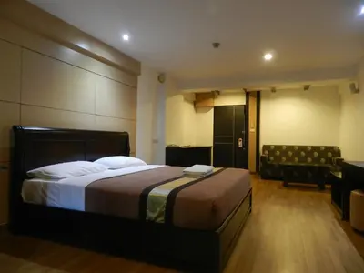 a hotel room with a bed and a chair at Nanatai Suites in Bangkok