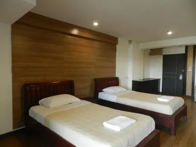 two beds in a room with wooden walls at Nanatai Suites in Bangkok