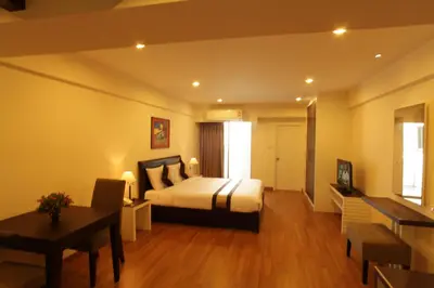 a bedroom with a bed and a table and a desk at Nanatai Suites in Bangkok