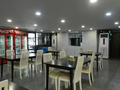 a dining room with tables and chairs and a television at Nanatai Suites in Bangkok