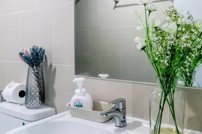 a bathroom sink with a vase of flowers and a mirror at TC Contel at Bts Samrong in Ban Khlong Samrong