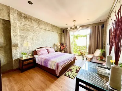 a bedroom with a bed and a table and a couch at WiNNiNE Cozy Home in Bangkok