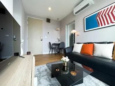a living room with a black couch and a table at Prime Sukhumvit Stay 1 BR - Fast WiFi - BTS Udomsuk in Bangkok