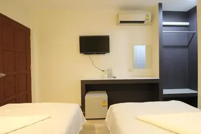a room with two beds and a sink and a tv at Chaiwat Guesthouse in Bangkok