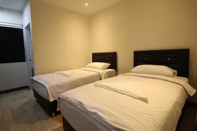 two beds in a room with white sheets and pillows at Chaiwat Guesthouse in Bangkok