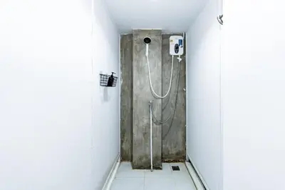 a bathroom with a shower in a white room at xx The Hidden Khaosan Road เดอะ ฮิดเด้น ถนนข้าวสาร - รามบุตรี in Bang Bua Thong Railway Station