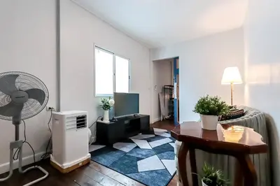 a living room with a table and a fan at Charming 2-Storey House in Bang Son, Bangkok in Bangkok