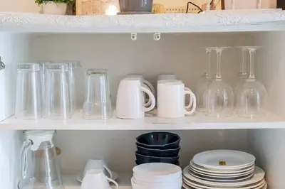 a shelf filled with glasses and bottles and plates at Charming 2-Storey House in Bang Son, Bangkok in Bangkok