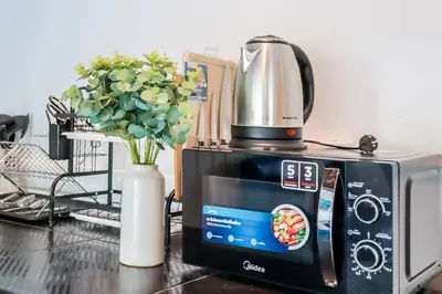 a microwave with a coffee pot on top of it at Charming 2-Storey House in Bang Son, Bangkok in Bangkok