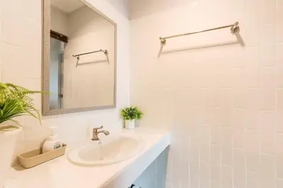 a white bathroom with a sink and a mirror at Charming 2-Storey House in Bang Son, Bangkok in Bangkok