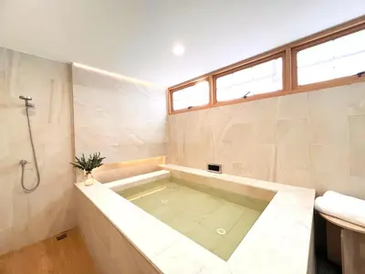 a bath tub in a bathroom with a window at Onsen Wellness Retreat House in Bangkok