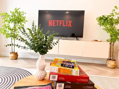 a living room with a tv and a table with books at Onsen Wellness Retreat House in Bangkok