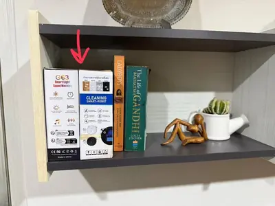 a shelf with books and a pair of shoes on it at Octopus Suite on HighRise, Skytrain, Fast Wifi and AC in Amphoe Phra Khanong