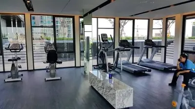 a man sitting on a bench in a gym at Octopus Suite on HighRise, Skytrain, Fast Wifi and AC in Amphoe Phra Khanong