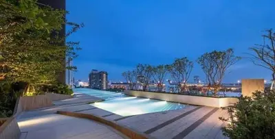 a swimming pool with a view of a city at night at Luxury Riverside condo in Nonthaburi