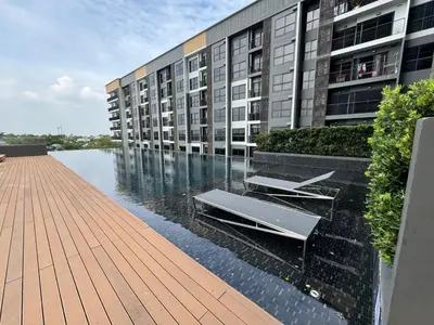 a building with a swimming pool in front of a building at Luxury Riverside condo in Nonthaburi