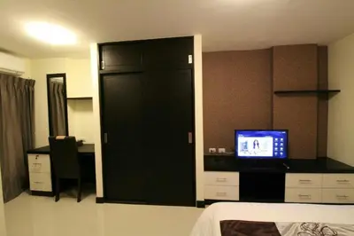 a room with a bedroom with a bed and a television at Leelawadee Modern Resort Huaykwang - ลีลาวดี ห้วยขวาง in Bangkok