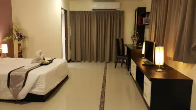 a hotel room with a bed and a desk with a television at Leelawadee Modern Resort Huaykwang - ลีลาวดี ห้วยขวาง in Bangkok
