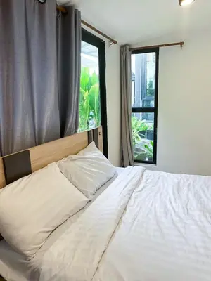 a bedroom with a white bed with a window at Chubbi 5 Room1 in Ban Bang Bamru