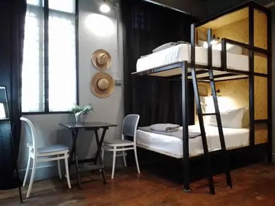 a room with two bunk beds and a table and chairs at Bangkok Bed and Bike in Bangkok
