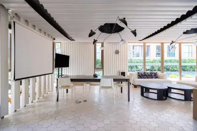 a living room with a projector screen and a table and chairs at Chambers cher ratchada ramintra in Ban Baen Phichit