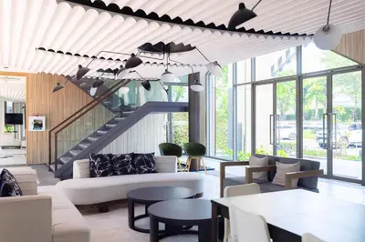 a living room with a staircase with chairs and tables at Chambers cher ratchada ramintra in Ban Baen Phichit