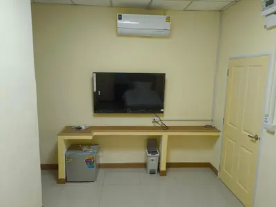 a room with a desk with a television on a wall at UOKResort in Ban Khlong Yuan