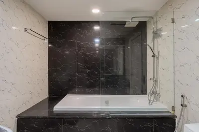 a bathroom with a bath tub with a black marble wall at State tower High Floor City View Lovely Unit in Bangkok