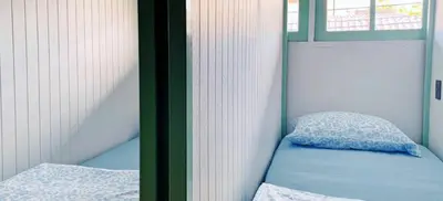 a small room with a bed and a pillow at The Hide Out Rambuttri Hostel in Bang Bua Thong Railway Station