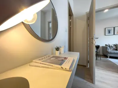 a book on a counter in a room with a mirror at Luxury 2BR︱Fast WiFi︱Walk to Central & MRT Rama 9 in Bangkok