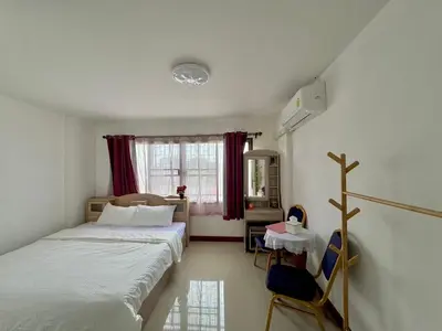 a bedroom with two beds and a table and a window at Baan Alisa 12 in Nonthaburi