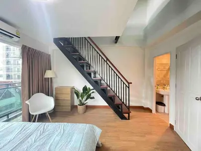 a bedroom with a staircase and a bed and a chair at Modern 5-Bedroom Townhome near MRT and Local Charm in Bangkok