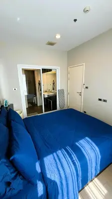 a large blue bed in a bedroom with a mirror at 1BR Thonglor BTS InfinityPool overlooking city in Bangkok