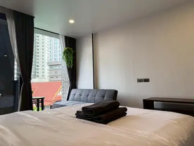 a bedroom with a bed with a chair and a window at Cozy Mini Theatre - Victory Monument - 3 pax in Bangkok
