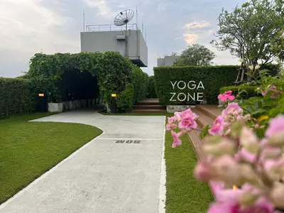 a building with a yoga zone sign and pink flowers at Cozy5Living in Bangkok 60m to MRT near chatuchank in Ban Bang Khwang