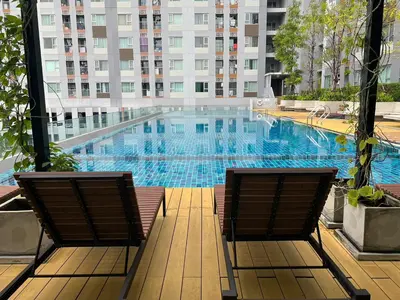 two chairs sitting next to a large swimming pool at Cozy7 Living in Bangkok60 m to MRTnear chatuchank in Ban Bang Khwang