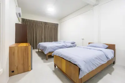 a bedroom with two beds and a television in it at WJ Luxury Sathorn in Bangkok