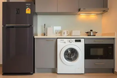 a kitchen with a washing machine and a refrigerator at BTS Thonglor Skyline Condo in Bangkok