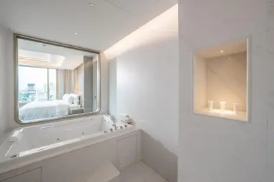 a white bathroom with a tub and a mirror at Grande Centre Point Prestige Bangkok in Bangkok