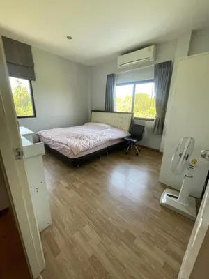 a bedroom with a bed and a desk and two windows at Maxim in Pak Kret