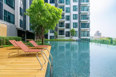 a swimming pool with two chairs and a building at BTS Thong Lor Top Floor City View in Bangkok