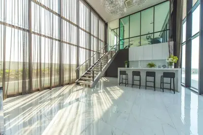 a large room with a staircase in a building with windows at Knightsbridge Duplex Tiwanon by Natcha in Nonthaburi