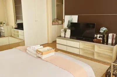 a bedroom with a television and a bed with towels at Cozy stylish home near Nana BTS in Bangkok