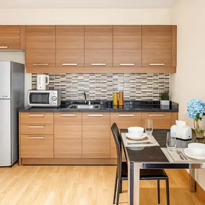 a kitchen with wooden cabinets and a table with chairs at Cozy stylish home near Nana BTS in Bangkok