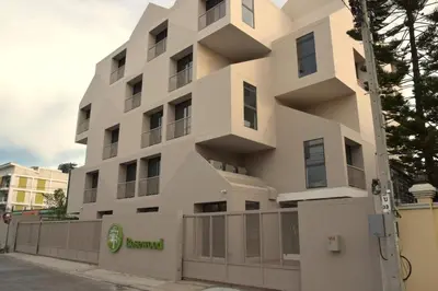 a white building with a fence in front of it at Rosewood Sridan in Ban Khlong Samrong