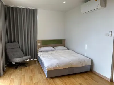 a bedroom with a bed and a chair at Rosewood Sridan in Ban Khlong Samrong
