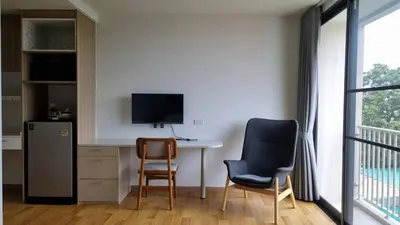a room with a desk and two chairs and a television at Rosewood Sridan in Ban Khlong Samrong