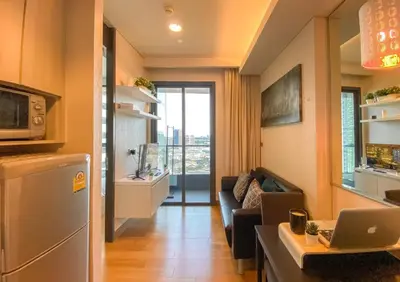 a living room with a couch and a laptop on a counter at River View Modern 1BR - Weekly Cleaning - Phrom Phong in Bangkok