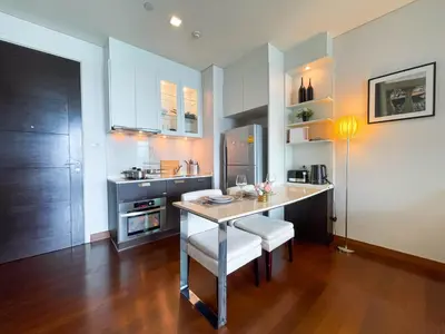a kitchen with a table and a kitchen with white cabinets at Near BTS Thong Lor l Workspace and Kitchen l Sontana in Bangkok
