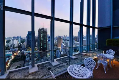 a balcony with tables and chairs and a view of a city at Hyde Sukhumvit 11 Bankok in Bangkok